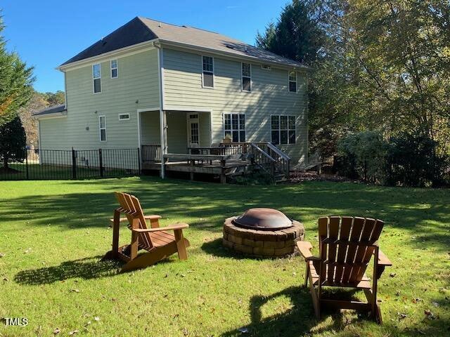 back of house with a lawn, a wooden deck, and a fire pit