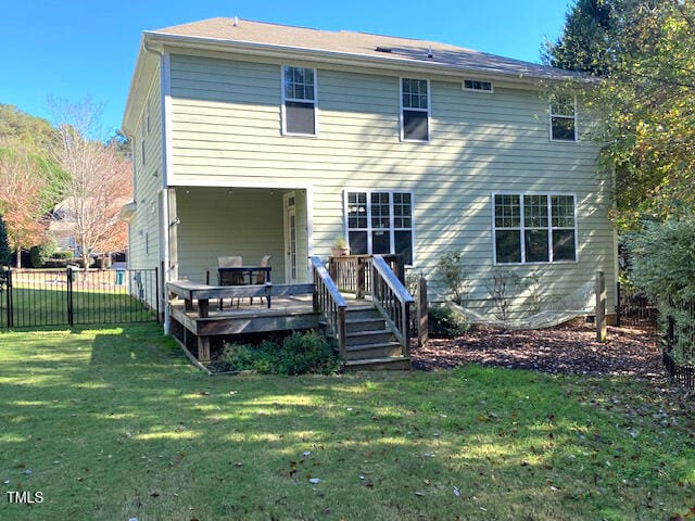 back of house featuring a lawn and a wooden deck