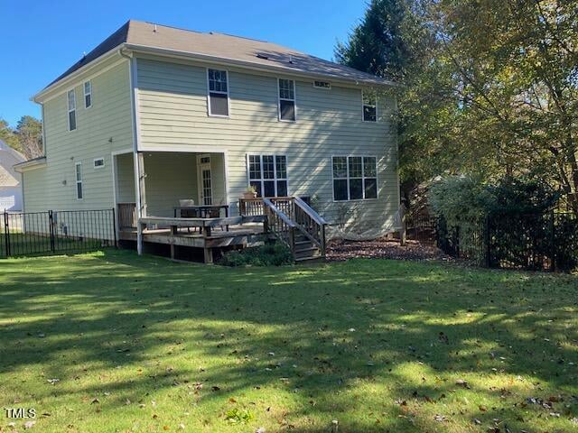 back of property featuring a lawn and a wooden deck