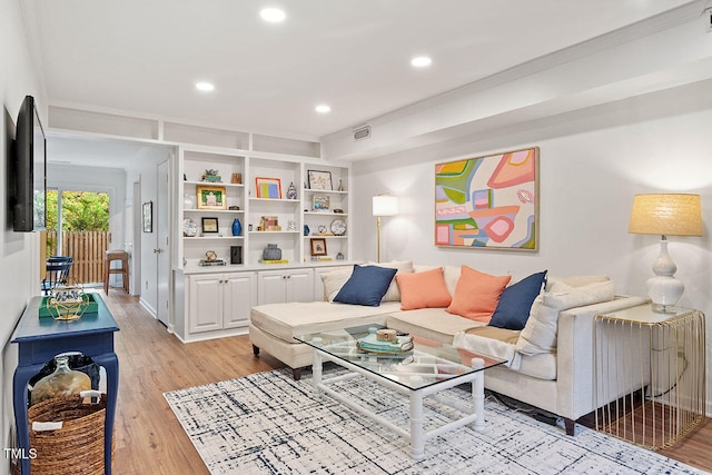 living room with light hardwood / wood-style flooring and ornamental molding