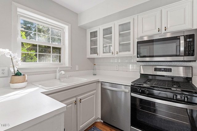 kitchen featuring hardwood / wood-style floors, sink, decorative backsplash, appliances with stainless steel finishes, and white cabinetry