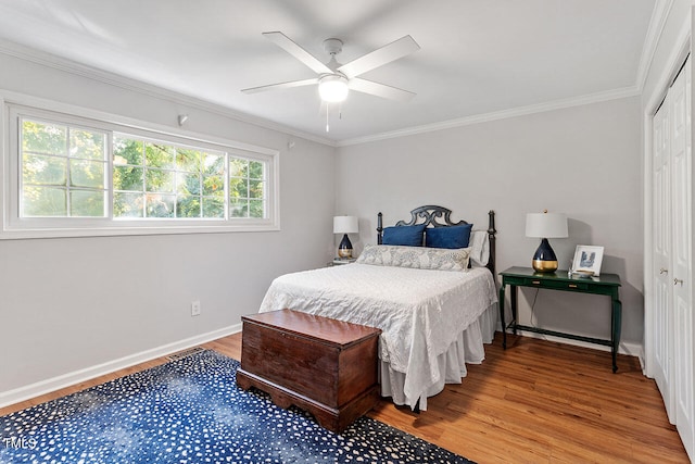 bedroom with hardwood / wood-style flooring, ceiling fan, crown molding, and a closet