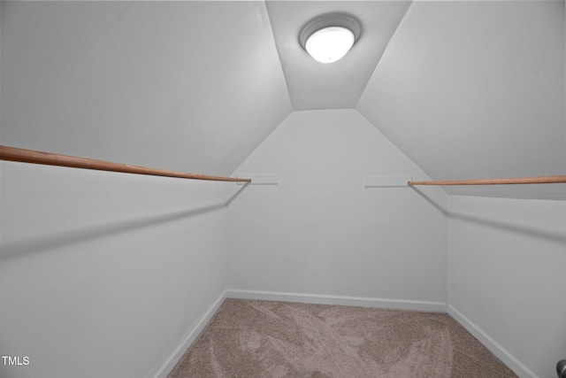 spacious closet with vaulted ceiling and light colored carpet