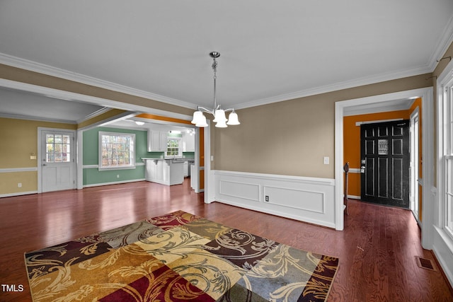 unfurnished dining area featuring ornamental molding, a notable chandelier, and dark hardwood / wood-style floors