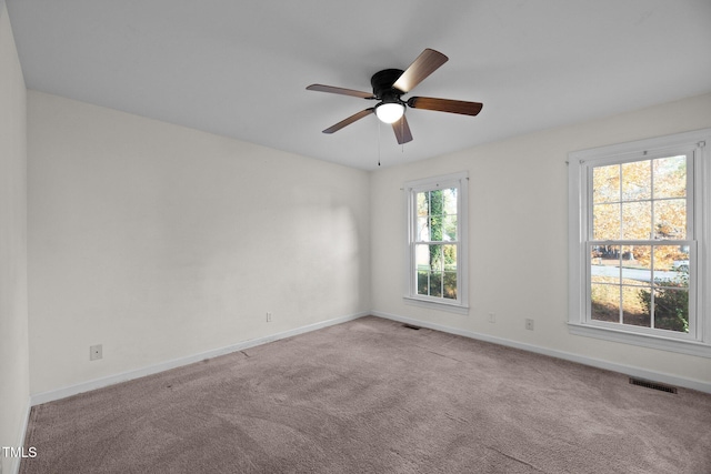 unfurnished room with plenty of natural light, light carpet, and ceiling fan