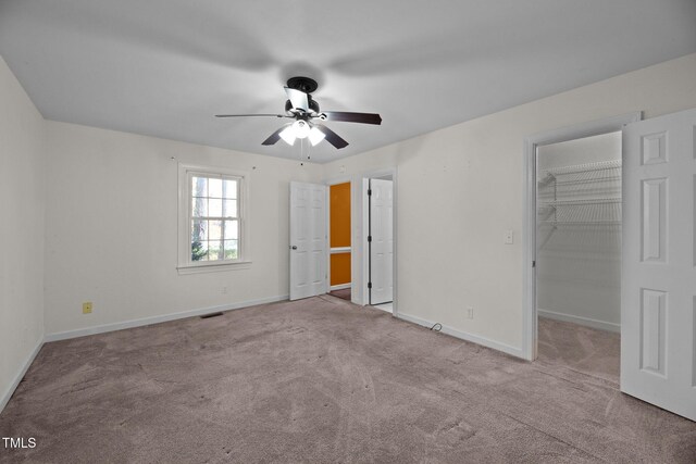 unfurnished bedroom featuring ceiling fan, light carpet, a closet, and a spacious closet