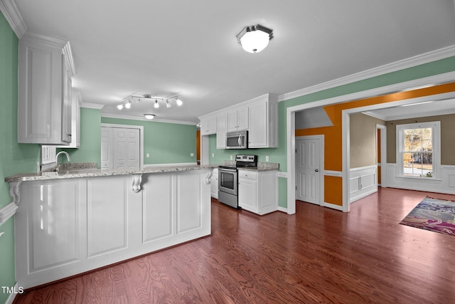 kitchen with stainless steel appliances, light stone counters, white cabinets, ornamental molding, and dark hardwood / wood-style floors