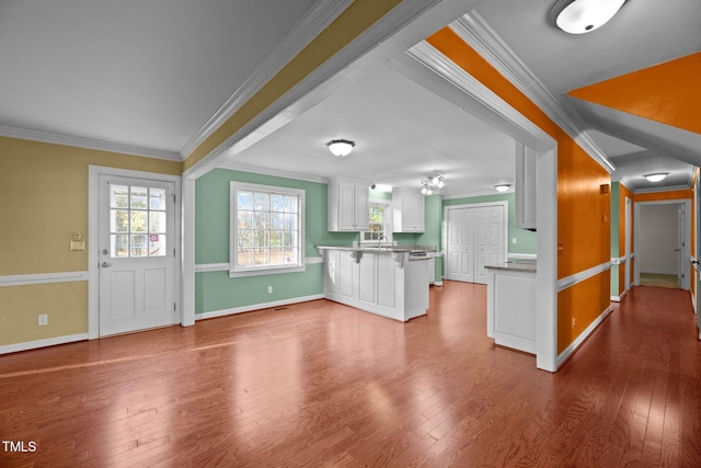 kitchen featuring white cabinets, a kitchen breakfast bar, ornamental molding, and hardwood / wood-style floors