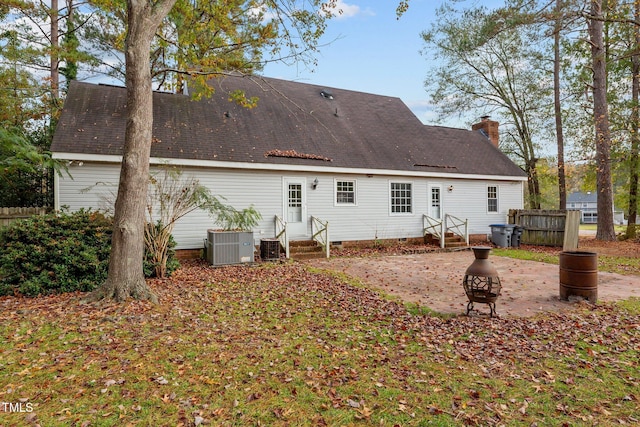 rear view of house with central air condition unit and a fire pit