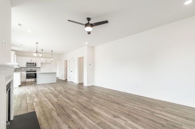 unfurnished living room featuring ceiling fan and light hardwood / wood-style flooring