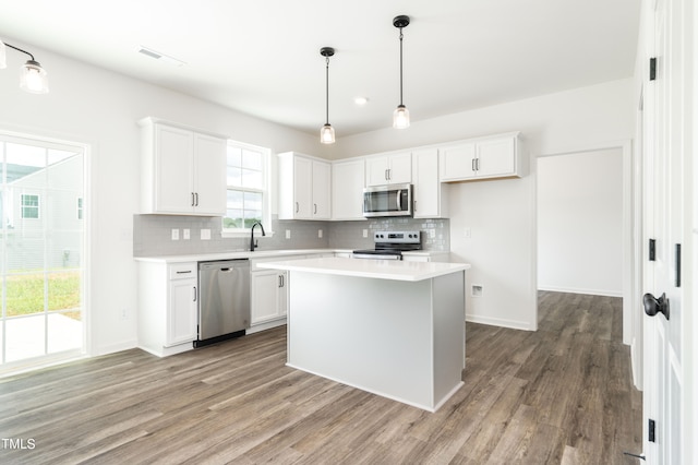 kitchen featuring stainless steel appliances, white cabinets, hardwood / wood-style floors, and a center island