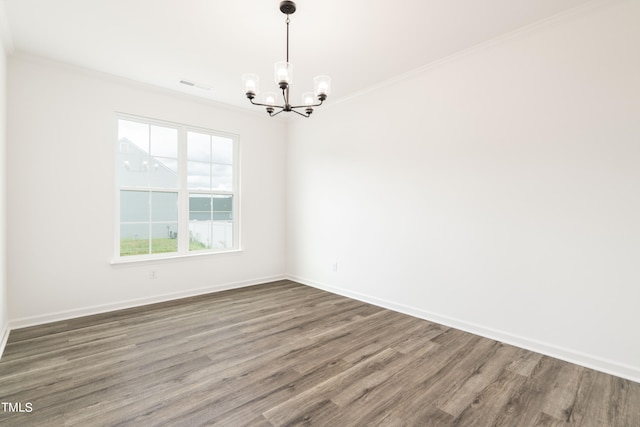 empty room with a chandelier, hardwood / wood-style flooring, and ornamental molding