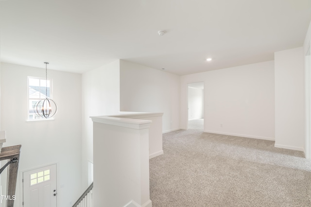 empty room featuring light carpet and a notable chandelier