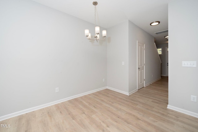 spare room featuring light hardwood / wood-style flooring and a notable chandelier