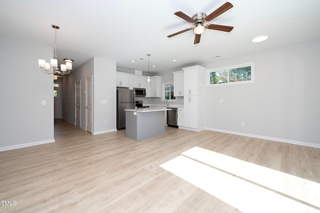 unfurnished living room featuring ceiling fan with notable chandelier and light hardwood / wood-style floors