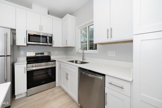 kitchen with white cabinetry, appliances with stainless steel finishes, sink, and light hardwood / wood-style flooring