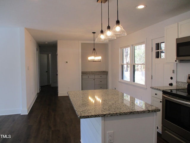 kitchen with dark hardwood / wood-style flooring, white cabinets, hanging light fixtures, a kitchen island, and appliances with stainless steel finishes