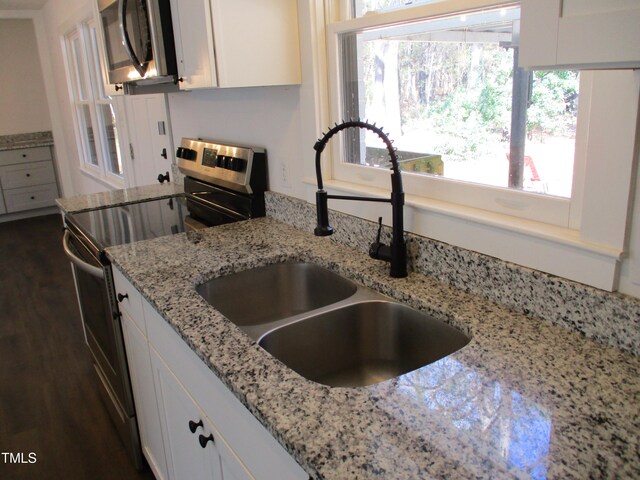 kitchen featuring dark wood-type flooring, white cabinets, sink, light stone countertops, and appliances with stainless steel finishes