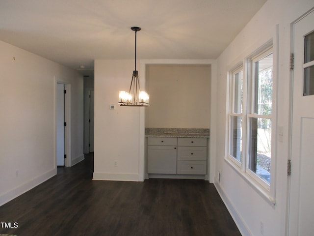 unfurnished dining area with dark hardwood / wood-style floors and a chandelier