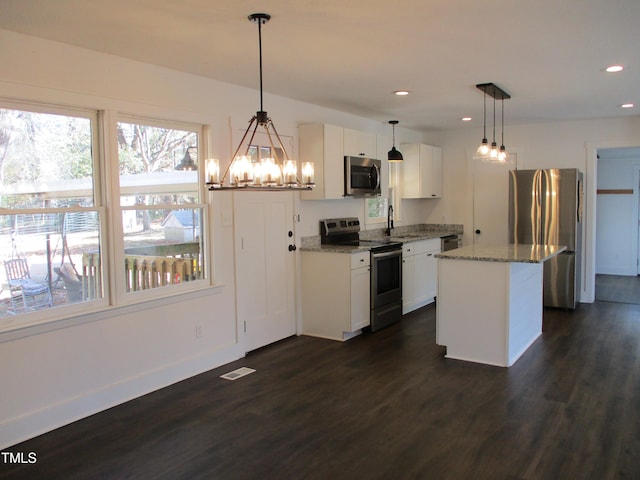 kitchen featuring stainless steel appliances, white cabinetry, decorative light fixtures, dark wood-type flooring, and a center island