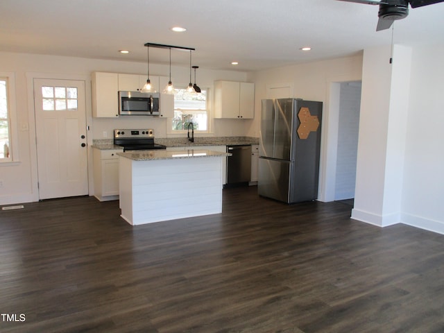 kitchen featuring white cabinetry, stainless steel appliances, decorative light fixtures, and plenty of natural light