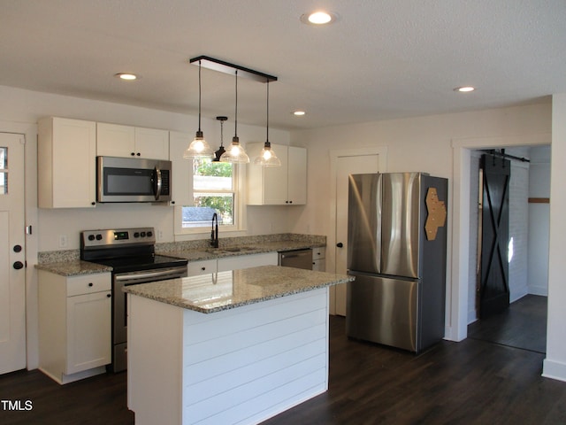 kitchen with a kitchen island, appliances with stainless steel finishes, a barn door, sink, and white cabinets