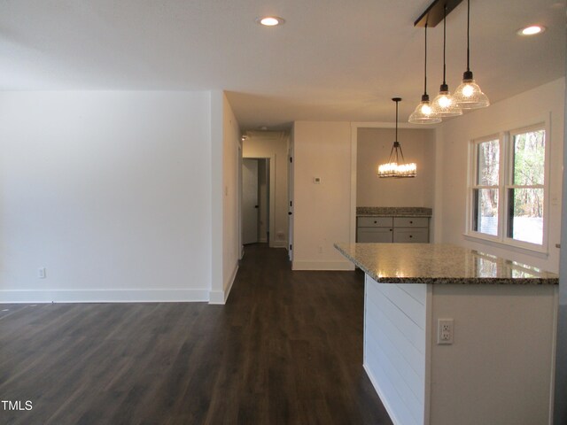 kitchen featuring dark stone countertops, hanging light fixtures, and dark hardwood / wood-style floors