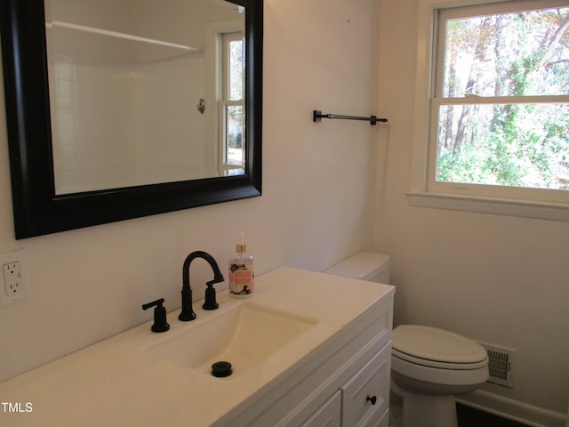 bathroom with a wealth of natural light, vanity, and toilet