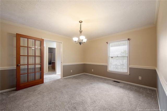 carpeted spare room with a chandelier, a textured ceiling, and crown molding