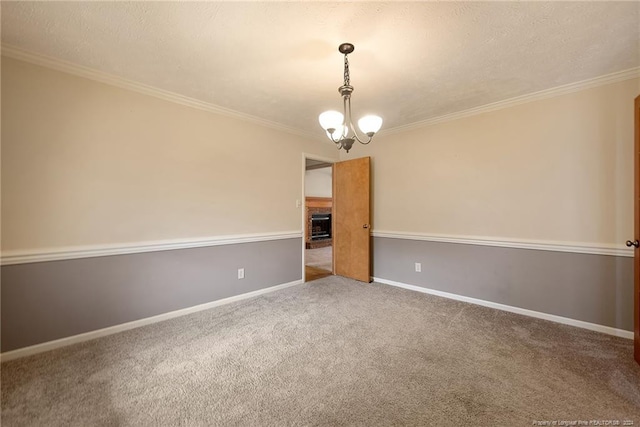 carpeted spare room featuring a chandelier, a textured ceiling, and ornamental molding