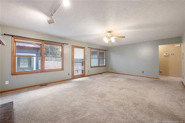 spare room featuring rail lighting, light carpet, a textured ceiling, and ceiling fan