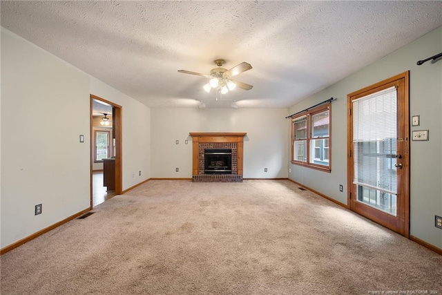 unfurnished living room with a textured ceiling, light colored carpet, ceiling fan, and a brick fireplace