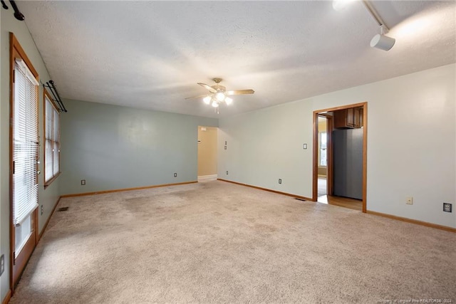 empty room featuring a textured ceiling, light carpet, and ceiling fan