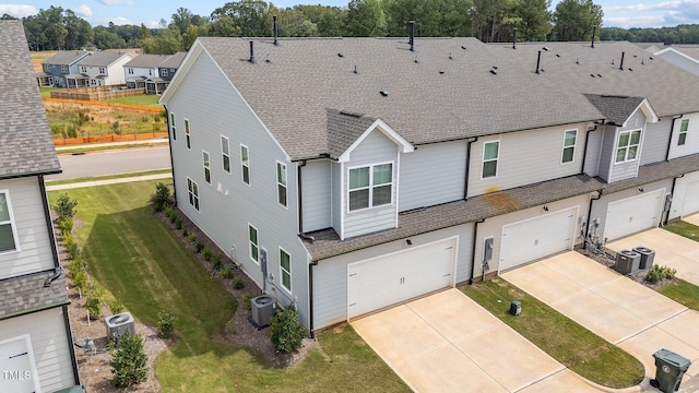 view of front of property with a front lawn, central air condition unit, and a garage