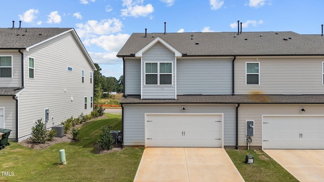 view of front of property with a garage, cooling unit, and a front yard