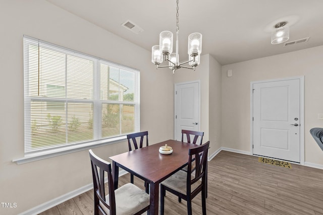 dining room with light hardwood / wood-style floors and an inviting chandelier