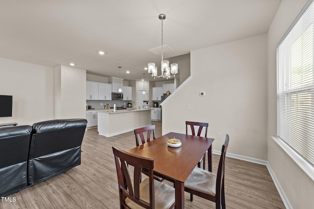 dining space featuring light wood-type flooring and an inviting chandelier