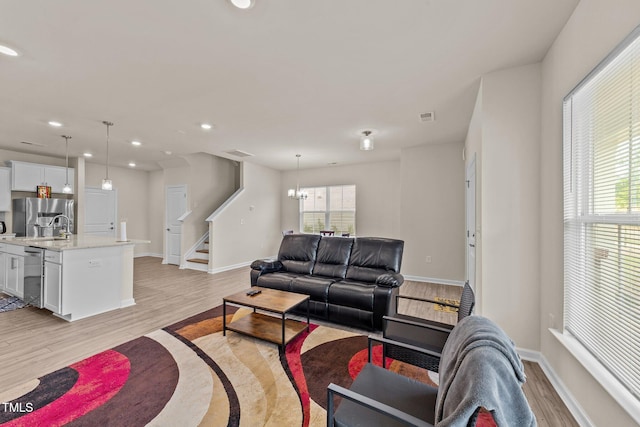 living room with light hardwood / wood-style flooring, a notable chandelier, and sink