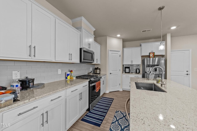 kitchen with white cabinets, appliances with stainless steel finishes, sink, and light hardwood / wood-style flooring