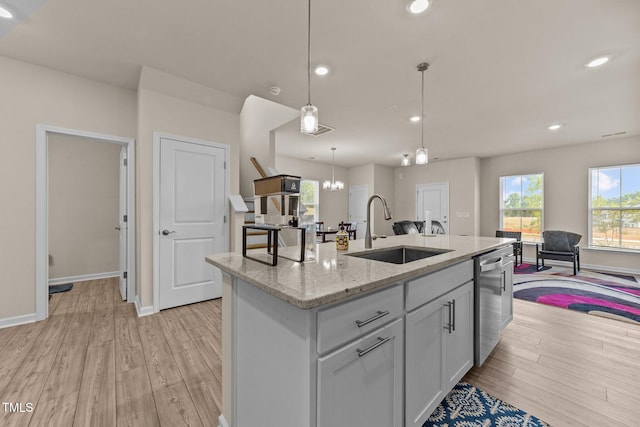 kitchen with light hardwood / wood-style floors, a center island with sink, dishwasher, sink, and light stone countertops