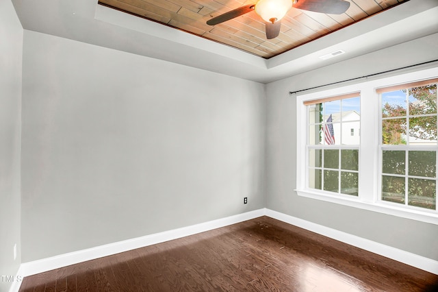 unfurnished room featuring dark wood-type flooring, ceiling fan, a tray ceiling, and wooden ceiling