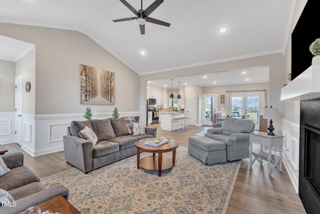 living room with light hardwood / wood-style floors, ornamental molding, vaulted ceiling, and ceiling fan