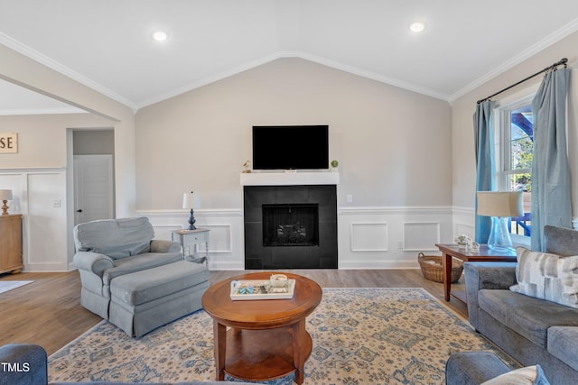 living room with lofted ceiling, hardwood / wood-style floors, a fireplace, and ornamental molding