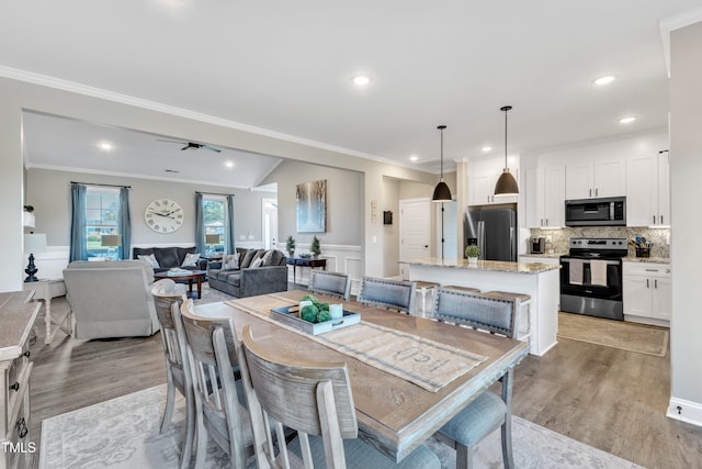 dining space with vaulted ceiling, light wood-type flooring, ceiling fan, and crown molding