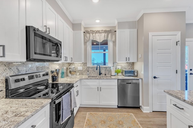 kitchen featuring stainless steel appliances, light wood-type flooring, light stone countertops, sink, and white cabinetry