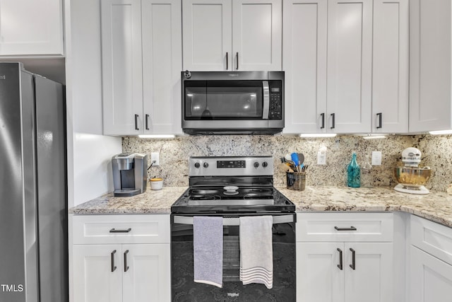 kitchen featuring backsplash, stainless steel appliances, light stone countertops, and white cabinets