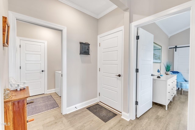 hallway featuring light wood-type flooring, crown molding, and a barn door