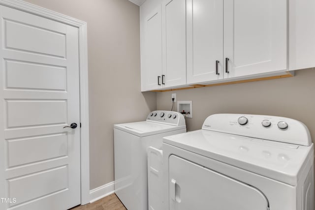 laundry area with washing machine and dryer, cabinets, and light hardwood / wood-style flooring