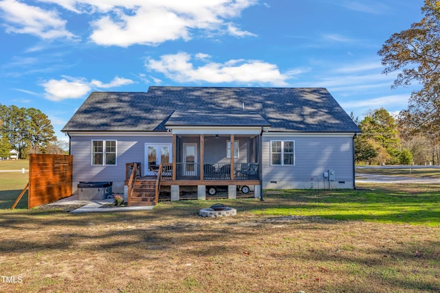 rear view of house featuring a deck, a fire pit, a sunroom, and a yard