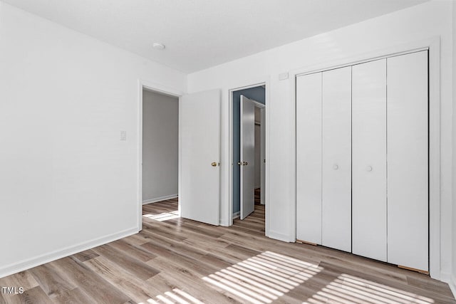 unfurnished bedroom with a textured ceiling, a closet, and light wood-type flooring